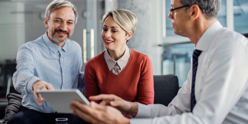 happy-mid-adult-couple-using-touchpad-with-their-financial-consultant-in-the-office--800x533